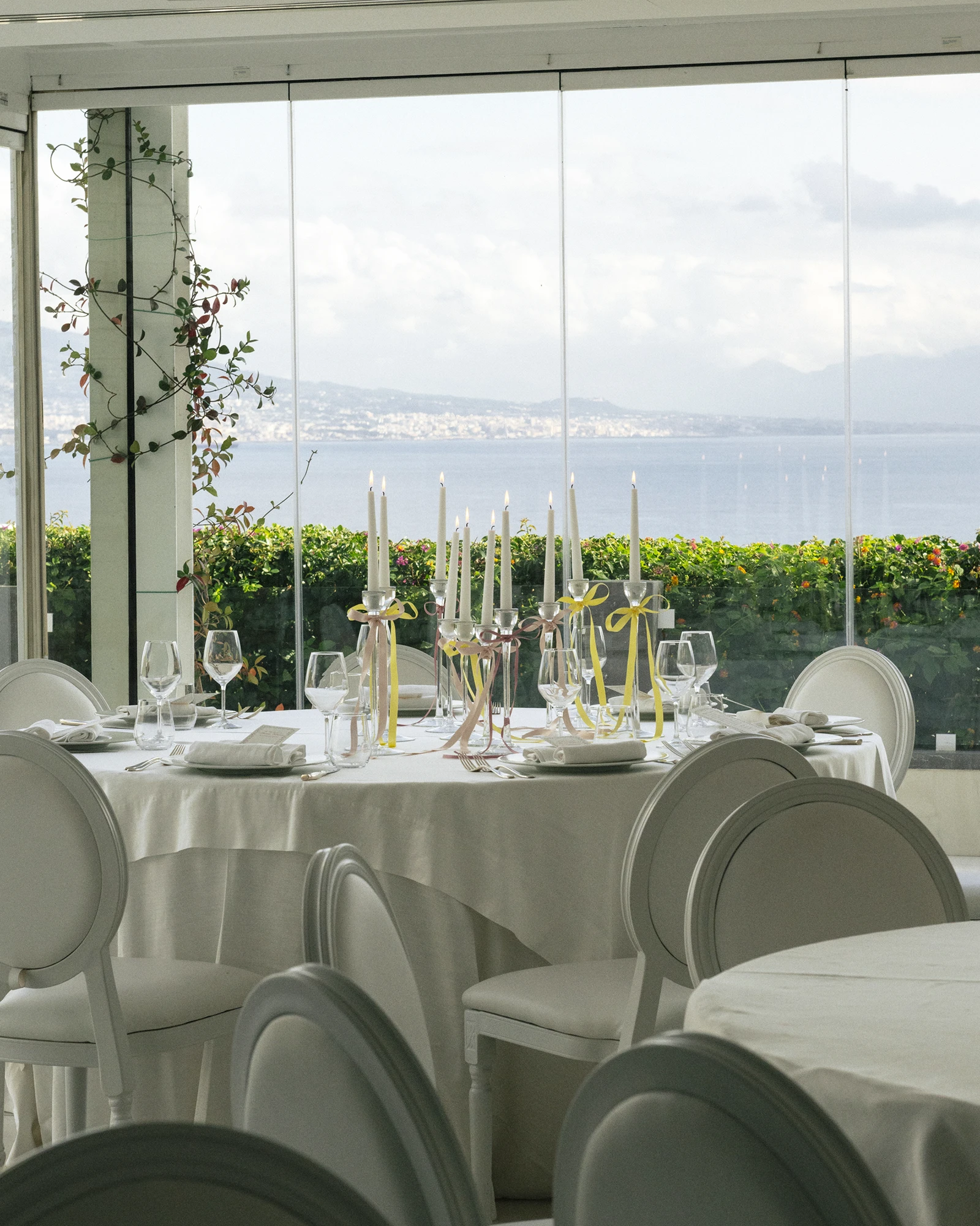 Il salone vetrato allestito con tavoli rotondi e vista sul golfo