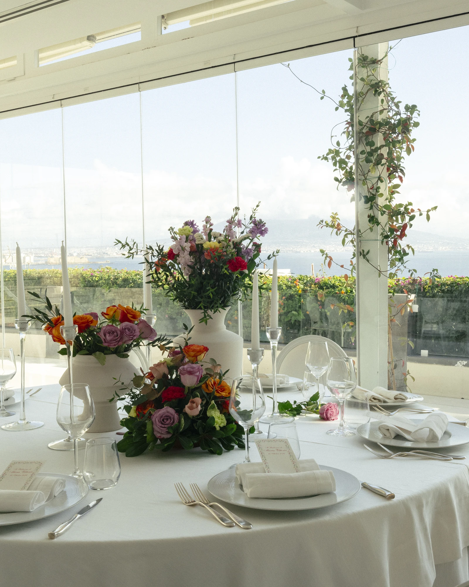 Mise en place con fiori e candele nel salone vetrato